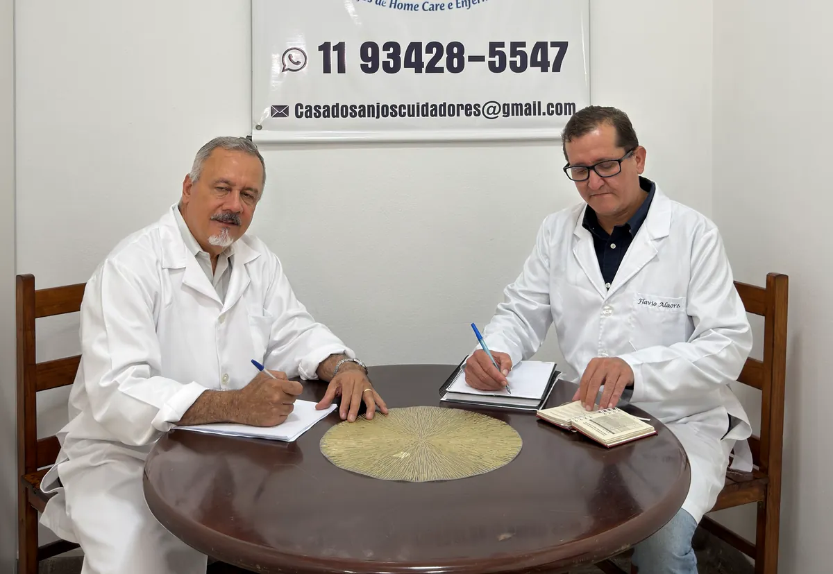 Daniel e Flávio, sócios da Casa dos Anjos, à mesa da sede preenchendo papéis